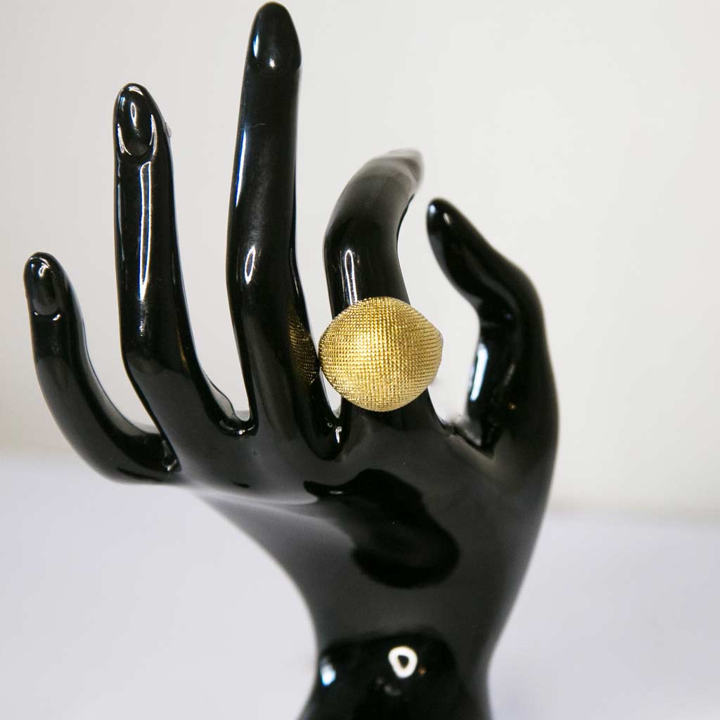 Main de mannequin portant à l'index une Bague dorée, en acier inoxydable,  en forme de boule, serti de petite perle dorée,