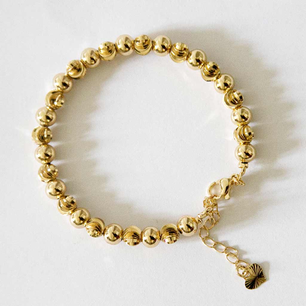 Bracelet en acier inoxydable, doré, constitué d'une suite de perle doré, avec un pendentif coeur,