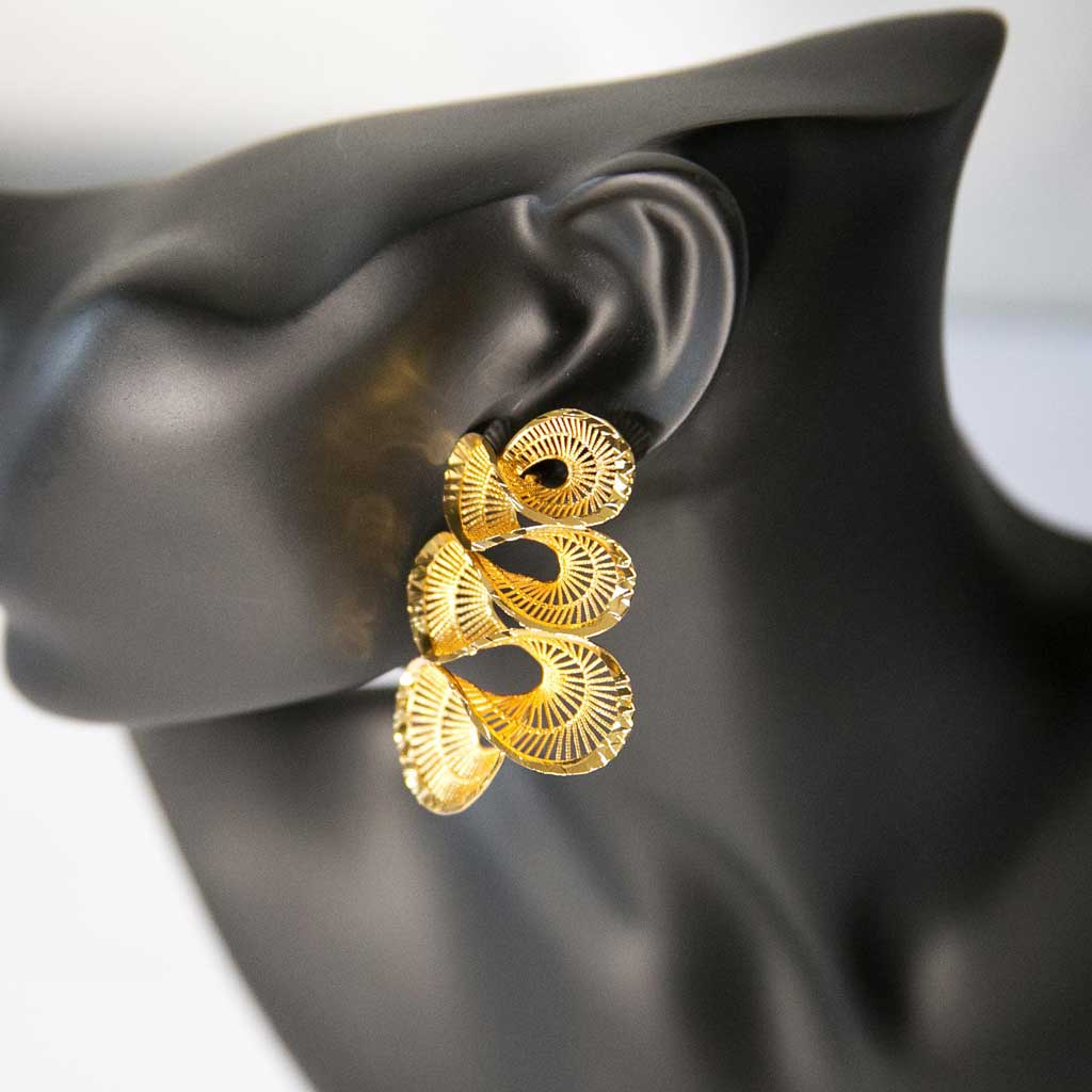 Tête de mannequin portant une boucle d'oreille dorée , en forme torsadée, en acier inoxydable