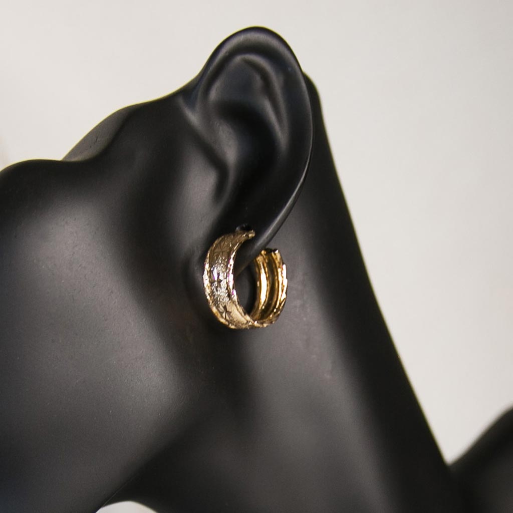 Tête de mannequin portant une petite boucle d'oreille dorée, en acier inoxydable, avec des motifs étoilées