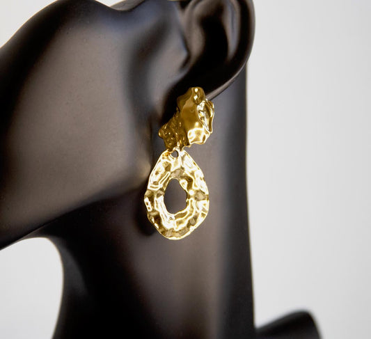 tête de mannequin portant boucle d'oreille dorée pendentif texture martelée