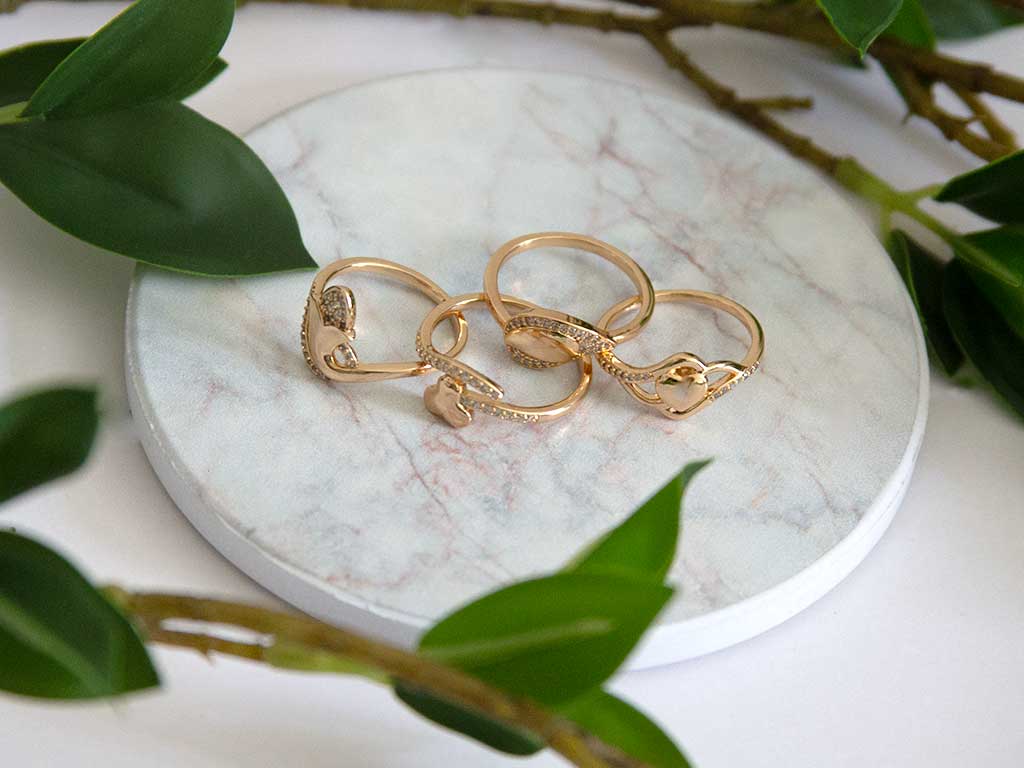 4 bagues dorées posées  sur un plateau en marbre