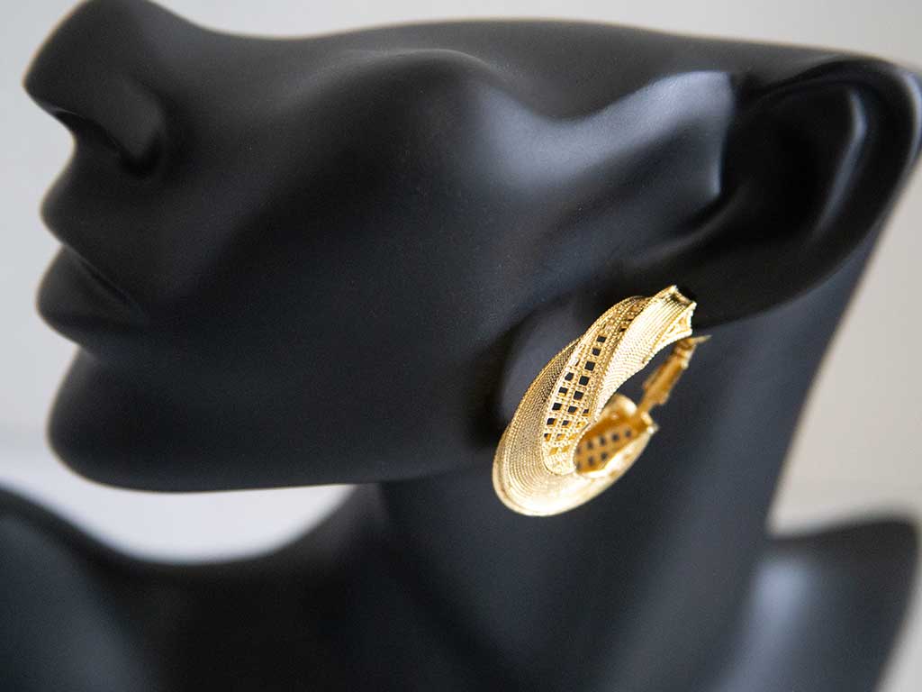 tête de mannequin portant une grosse boucles d'oreilles dorées en forme de boucle