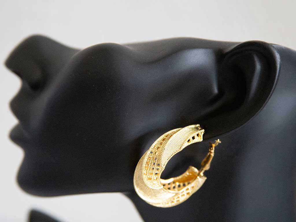 tête de mannequin portant une grosse boucles d'oreilles dorées en forme de boucle