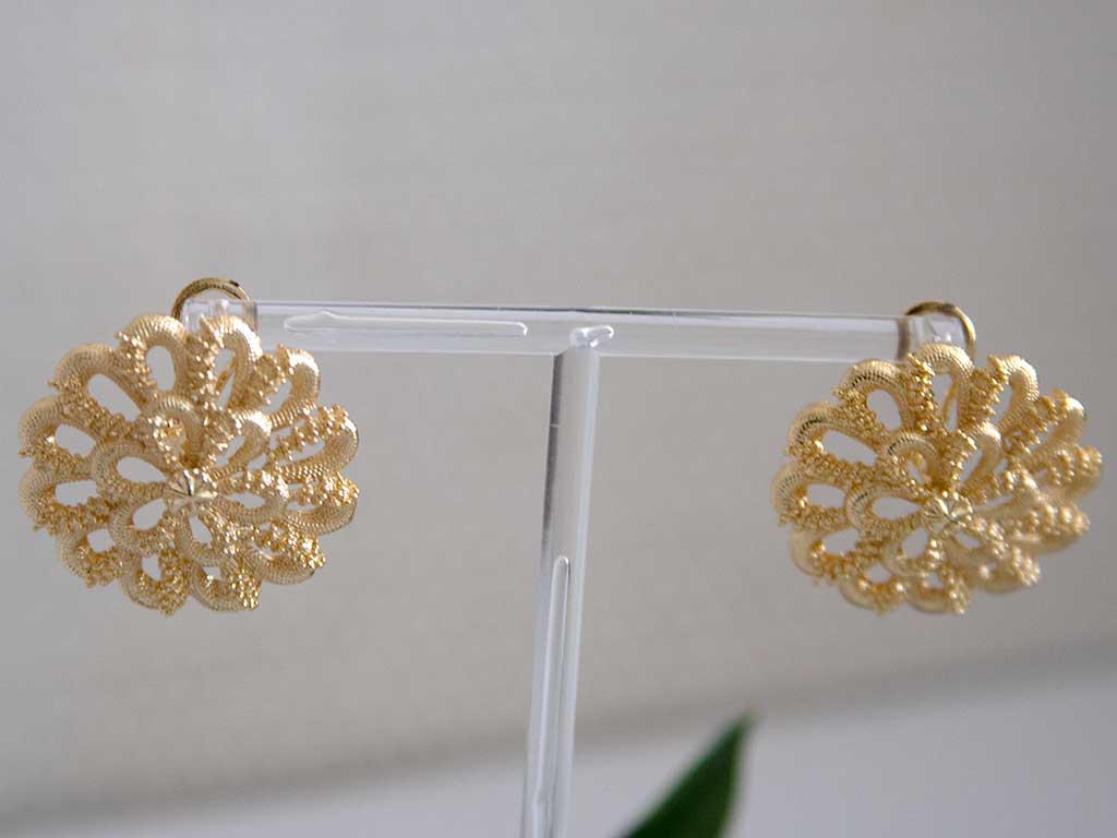 Grosses boucles d'oreilles dorées en forme de fleur sur un présentoir