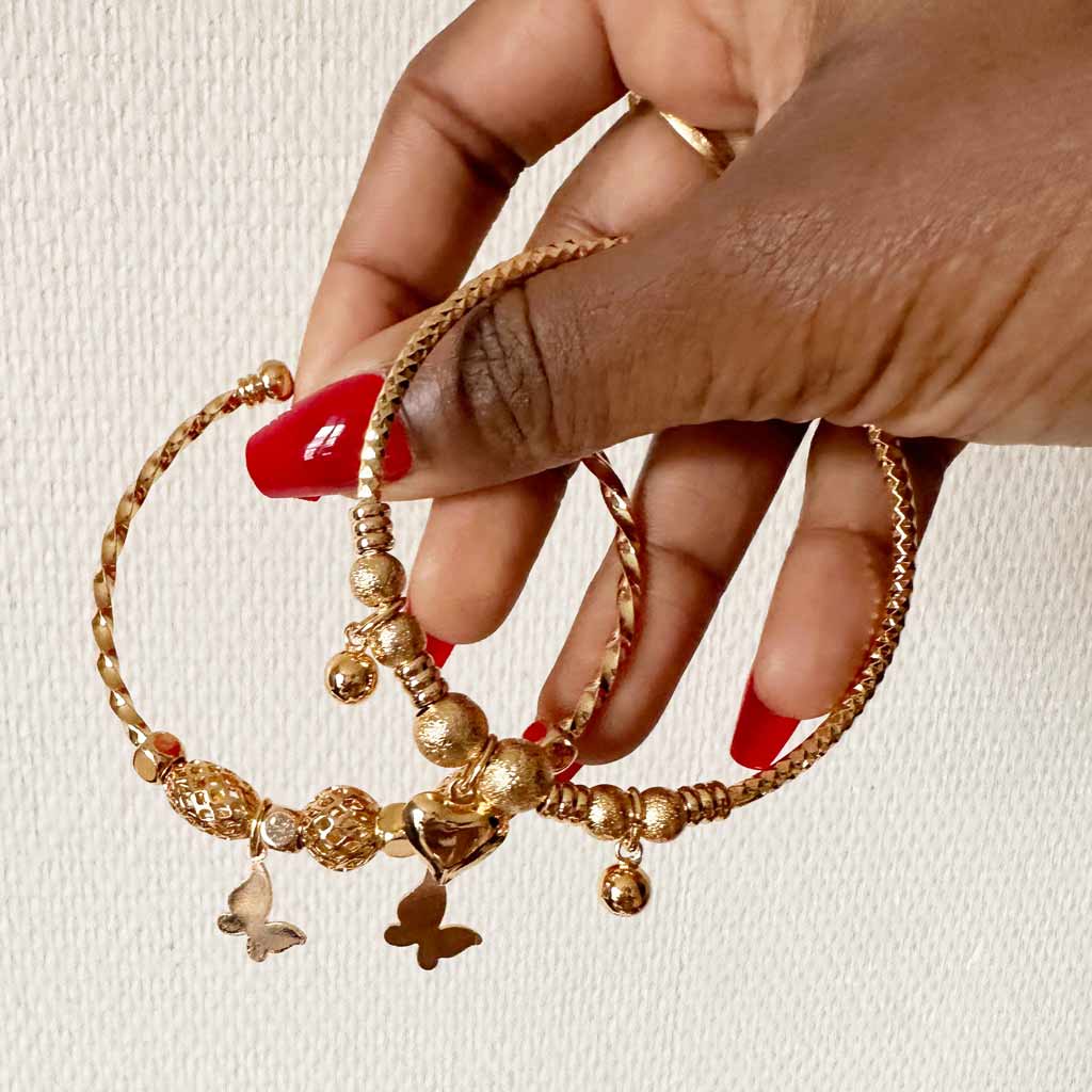 Main de femme tenant deux bracelets dorés