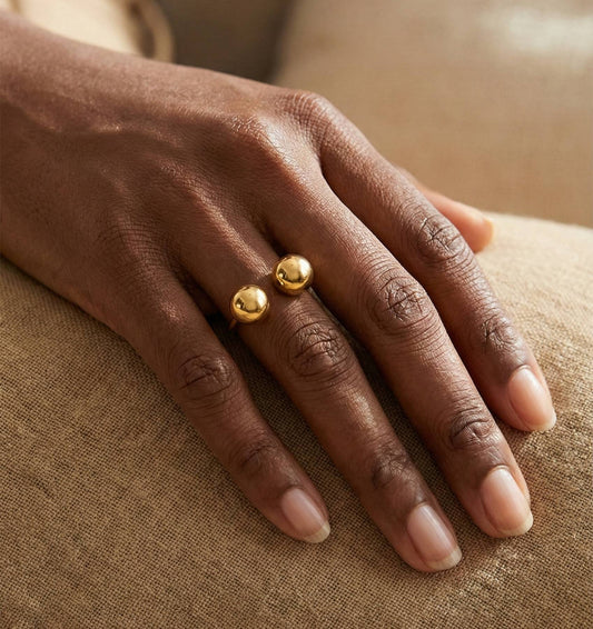 Main de femme portant la bague Bubble dorée ouverte avec double boule en acier inoxydable, design minimaliste – Lidiar Collection