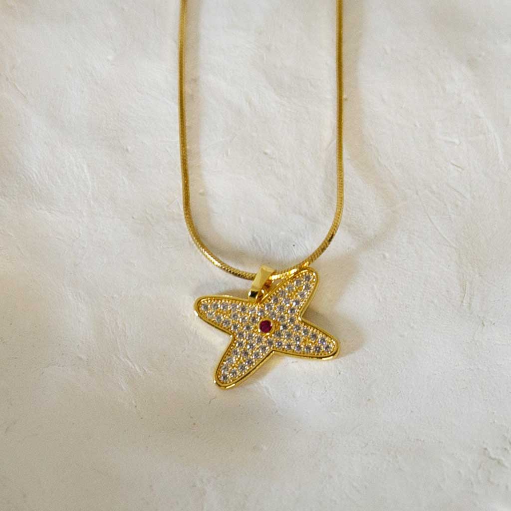 Collier doré avec un pendentif en forme de fleur avec des strass blanc et rouge