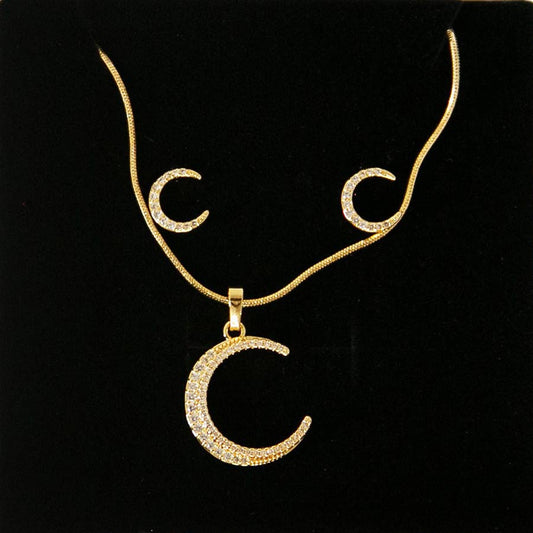 un ensemble de boucle d'oreille et de collier en forme de croissant de lune dans un écrin à bijoux