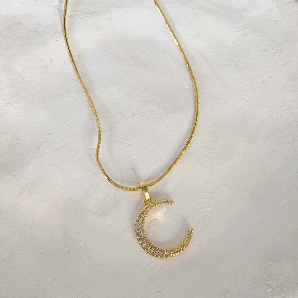 Collier doré avec un pendentif en forme de croissant de lune doré avec des strass