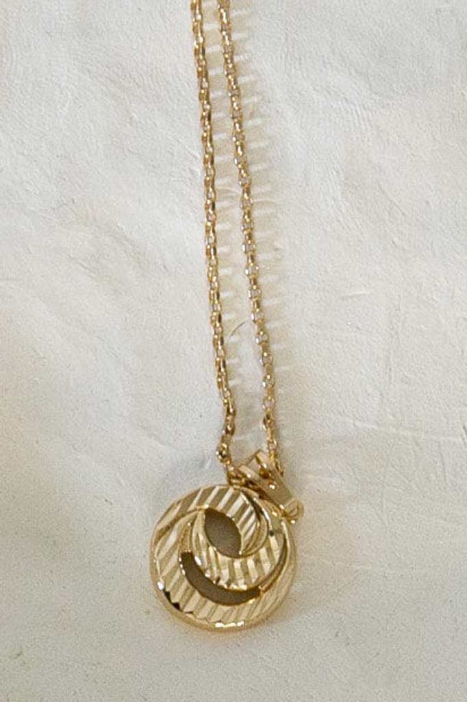 collier avec un pendentif en forme ronde posé sur un plateau