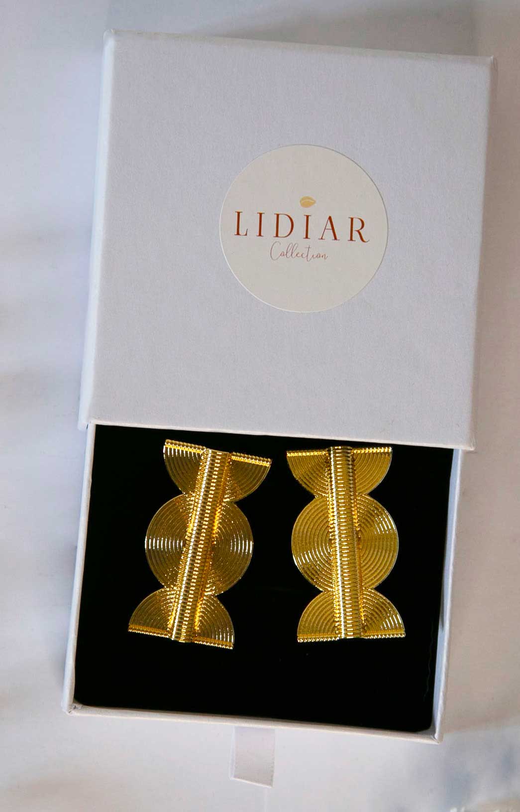 Boucles d'oreilles de style ethniques dorées dans un écrin à bijoux Lidiar collection