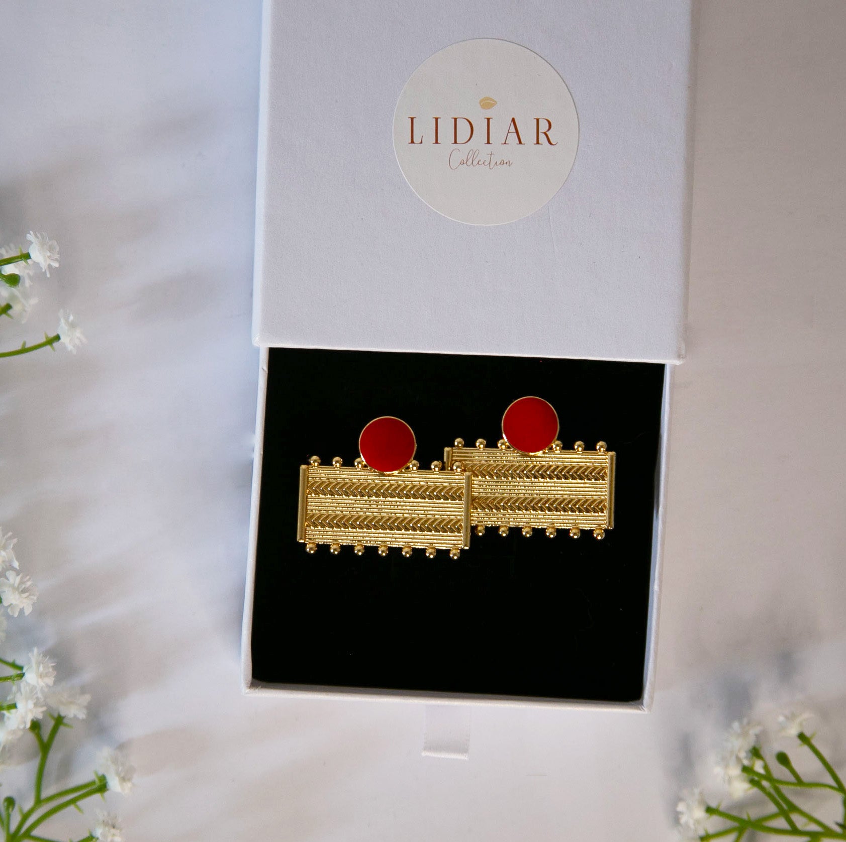 Boucles d'oreilles dorées et rouge, rectangulaires, avec des formes géométriques dans un écrin à bijoux lidiar collection
