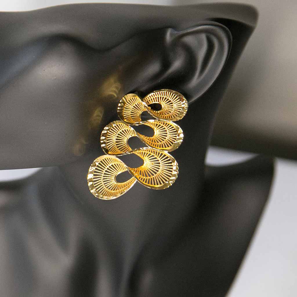 Tête de mannequin portant une boucle d'oreille dorée , en forme torsadée, en acier inoxydable
