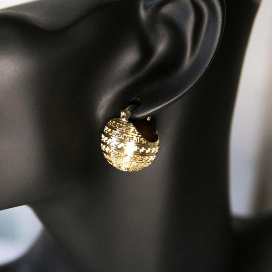 Tête de mannequin portant une boucle d'oreille dorée en forme de boule avec des motifs géométriques