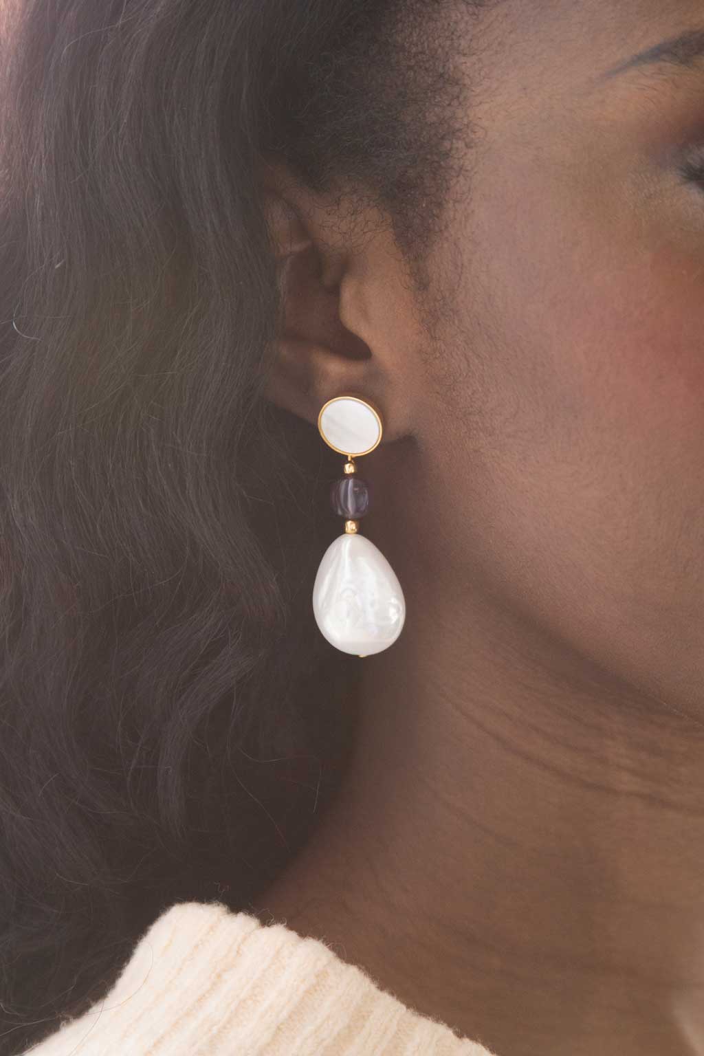 femme portant une boucle d'oreille nacrée avec perle et gemme améthyste