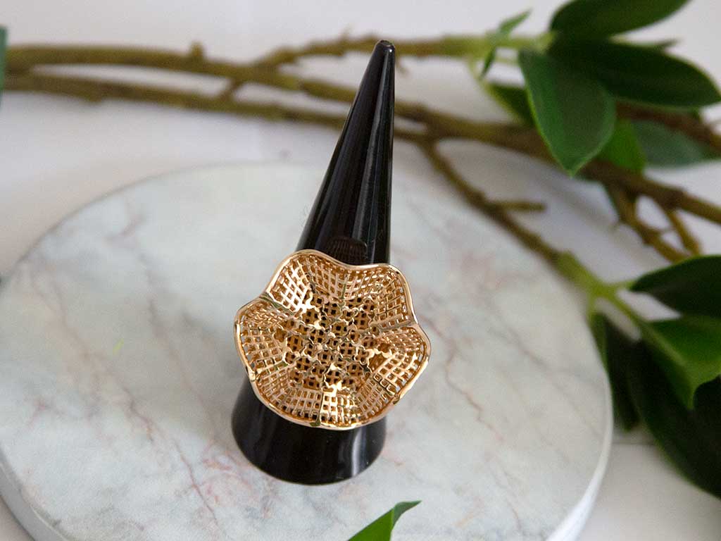 bague dorée en forme de fleure sur un présentoir à bague 