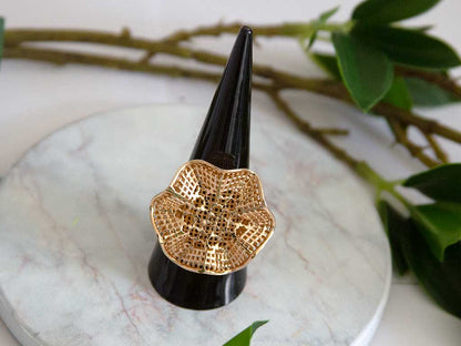 bague dorée en forme de fleure sur un présentoir à bague 