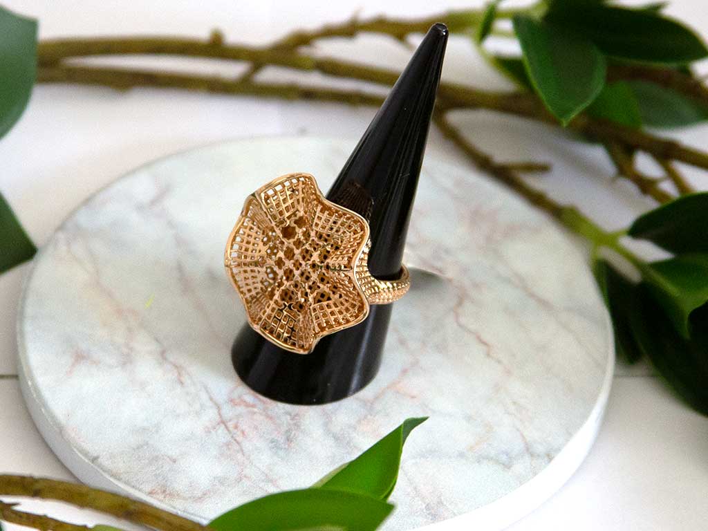 bague dorée en forme de fleure sur un présentoir à bague 