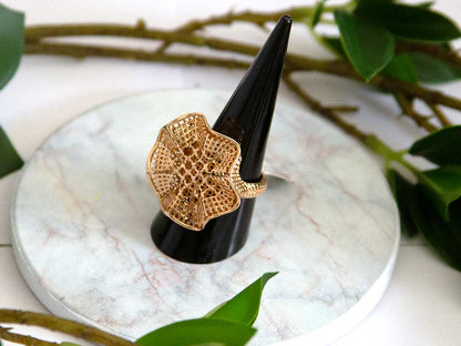 bague dorée en forme de fleure sur un présentoir à bague 