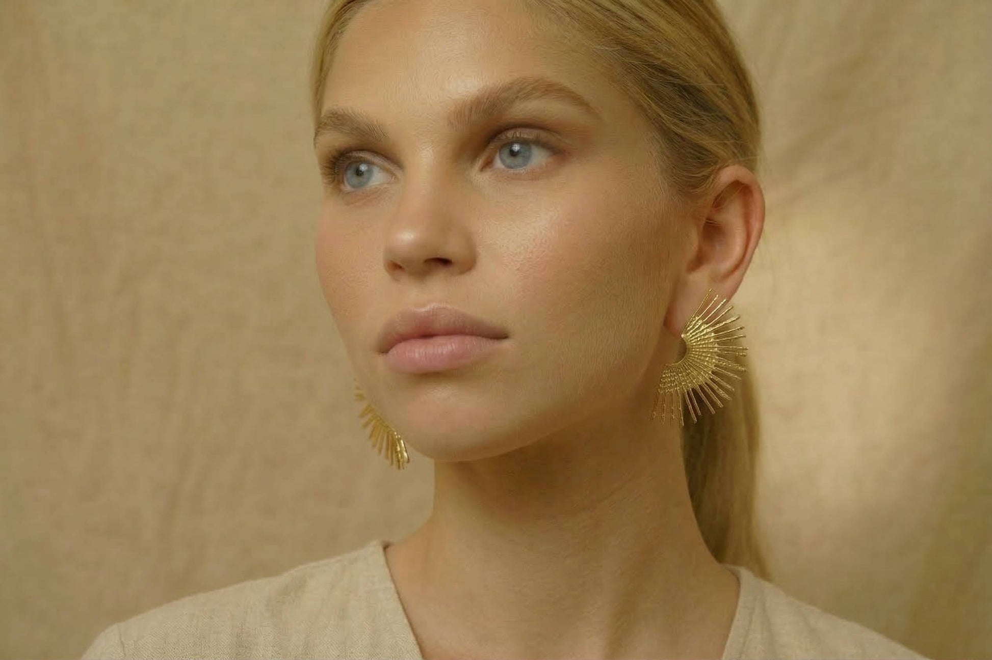 jeune femme blonde portant des Boucles d’oreilles dorées rayonnantes texturées, design éventail élégant – Lidiar Collection