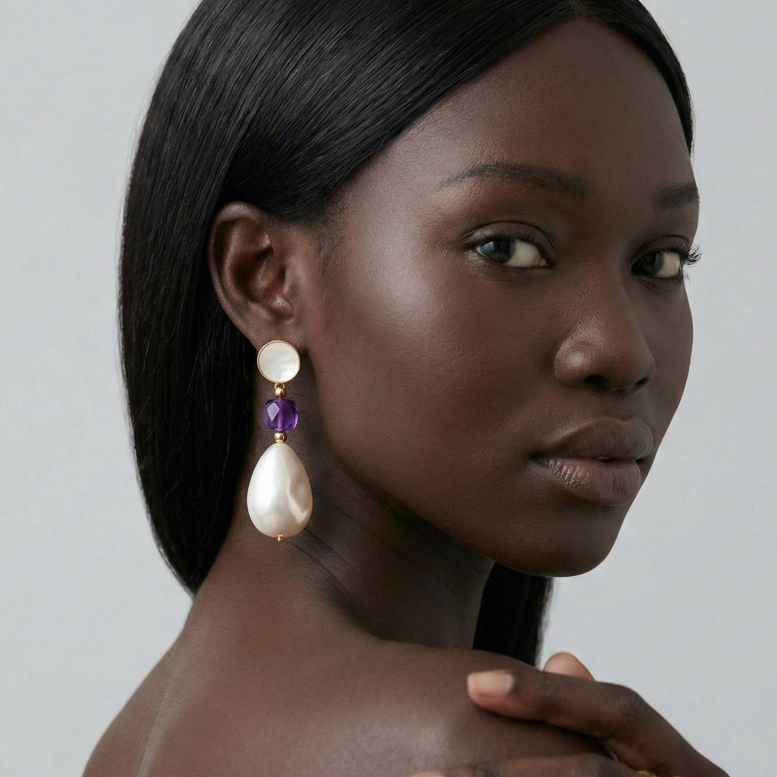 Jeune femme portant des Boucles d’oreilles pendantes dorées avec nacre naturelle, perle baroque et pierre violette style améthyste – bijou élégant Lidiar Collection