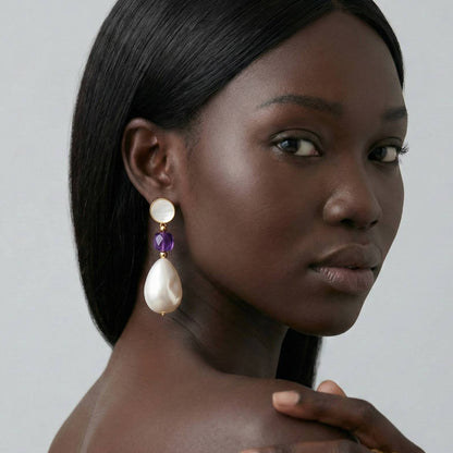 Jeune femme portant des Boucles d’oreilles pendantes dorées avec nacre naturelle, perle baroque et pierre violette style améthyste – bijou élégant Lidiar Collection