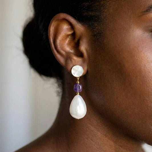 Jeune femme portant des Boucles d’oreilles pendantes dorées avec nacre naturelle, perle baroque et pierre violette style améthyste – bijou élégant Lidiar Collection