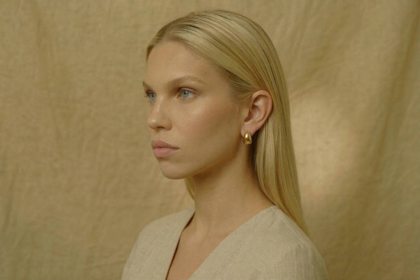 Jeune femme blonde portant des Boucles d’oreilles clip dorées rondes pour oreilles non percées en acier inoxydable – Lidiar Collection