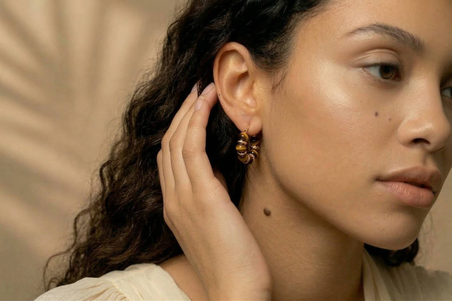 jeunne femme portant des Boucles d’oreilles créoles dorées avec perles marron effet ambre, design élégant – Lidiar Collection