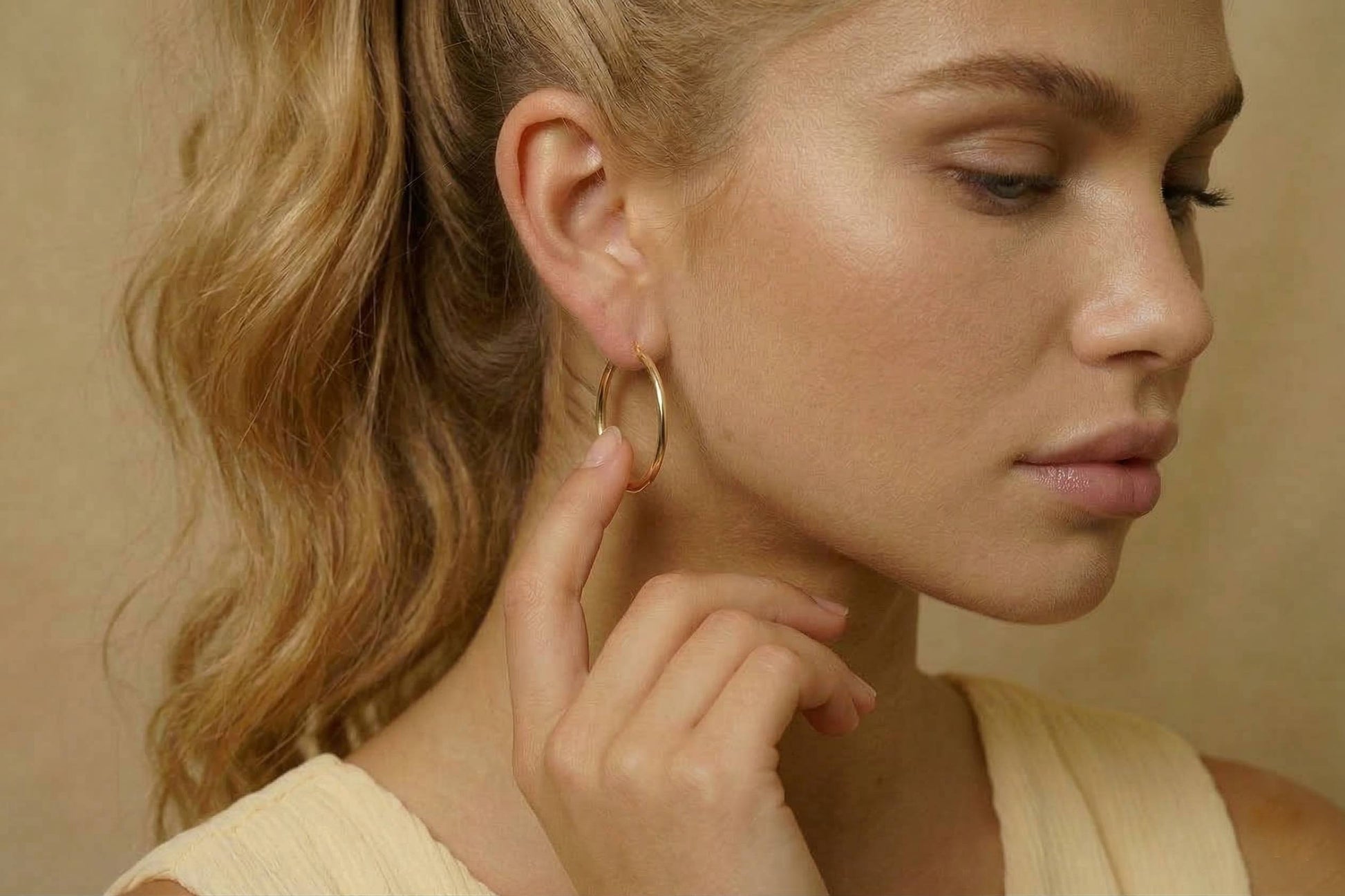 Jeune femme portant des Boucles d’oreilles créoles dorées fines en acier inoxydable, design minimaliste – Lidiar Collection
