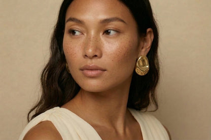 jeunne femme portant des Boucles d’oreilles dorées design organique en acier inoxydable, forme sculpturale élégante – Lidiar Collection