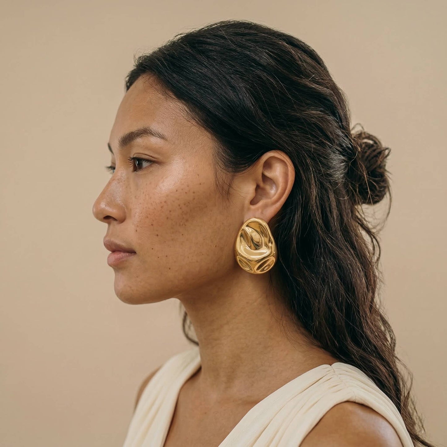 jeune femme portant des Boucles d’oreilles dorées design organique en acier inoxydable, forme sculpturale élégante – Lidiar Collection