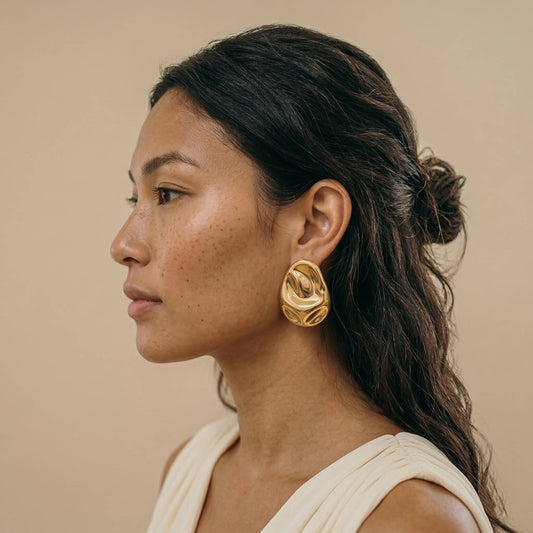 jeune femme portant des Boucles d’oreilles dorées design organique en acier inoxydable, forme sculpturale élégante – Lidiar Collection