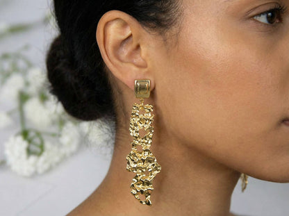 Jeune femme portant les boucles d'oreilles dorées effet martelé texturé en acier inoxydable - Modèle Siné par Lidiar Collection