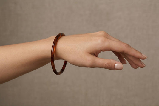 bras portant au poignet un Bracelet jonc en résine effet ambre marron foncé, design minimaliste et élégant – Lidiar Collection 