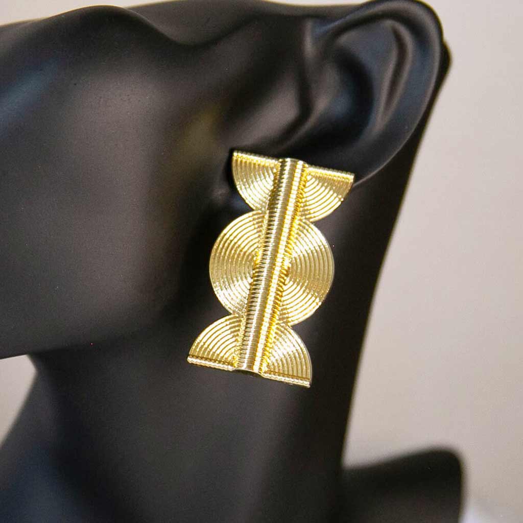 Tête de mannequin portant une boucle d'oreille de style ethnique, dorée