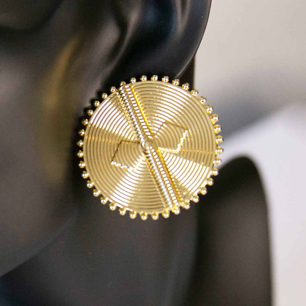Tête de mannequin portant une boucle d'oreille ronde ethnique dorées