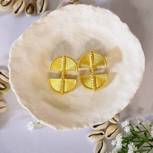 Boucles d'oreilles, style ethnique , dorée posées sur un plateau avec décor de coquillages cauris et fleures blanches