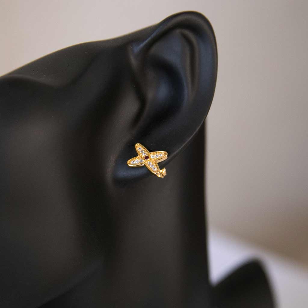 Tête de mannequin portant une boucle d'oreille en forme de fleur , dorée, avec des strass blanc et rouge